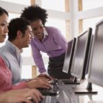 Two adults in a conversation while looking at the computer screen.