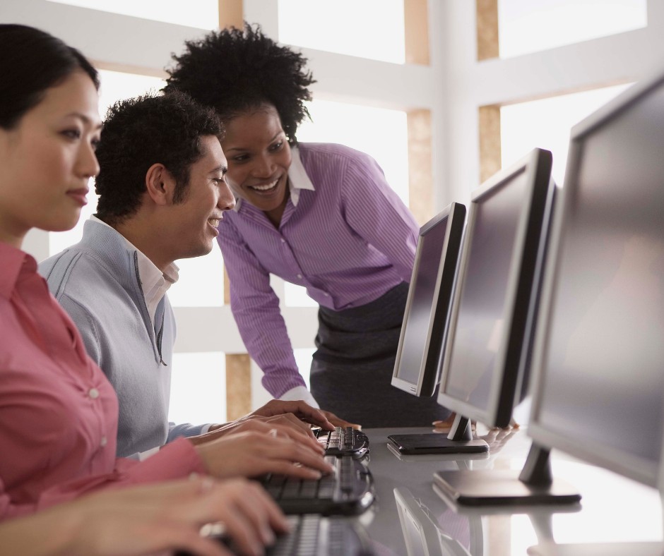 Two adults in a conversation while looking at the computer screen.