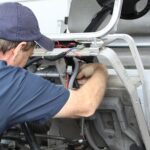 Technician using Club Car service tools for maintenance on a utility vehicle, highlighting Jeffrey Allen Inc.'s expert service.