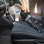 Man Vacuuming a Car interior with hose and brush attachment