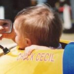 Becca Bertok holding her baby at a race track, showcasing early exposure to motorsports