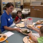 children partake in a family style dinner with their caregiver