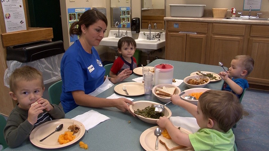 children partake in a family style dinner with their caregiver