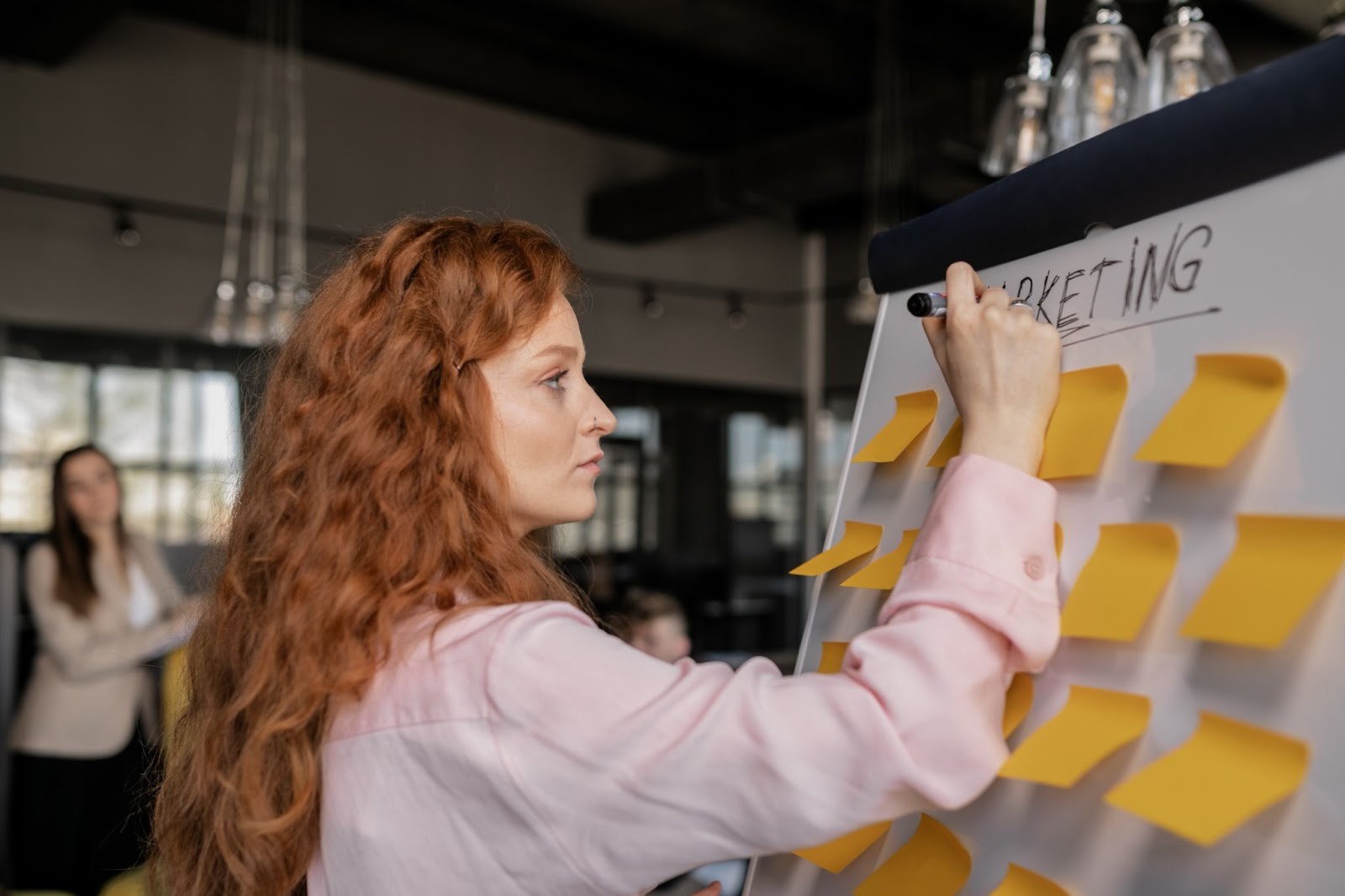 Woman brainstorming child care marketing strategies on a whiteboard with sticky notes